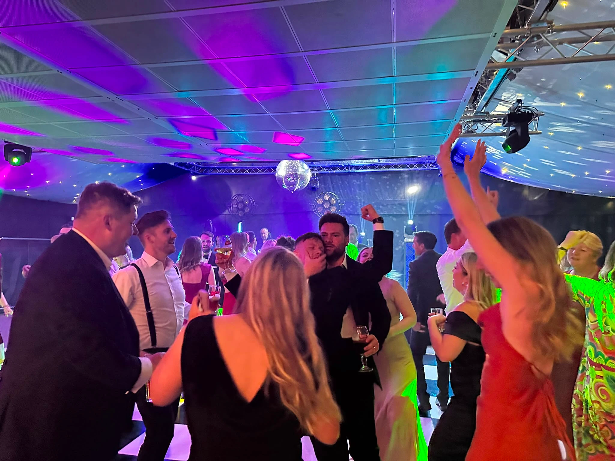 Black-tie guests under marquee truss and a mirrorball
