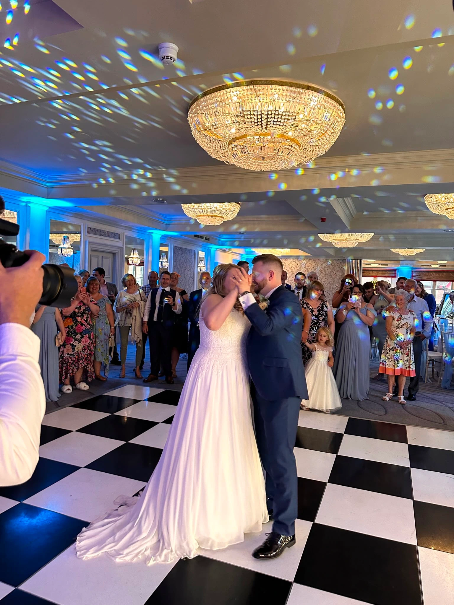 First dance under the chandeliers on a black and white checkerboard floor