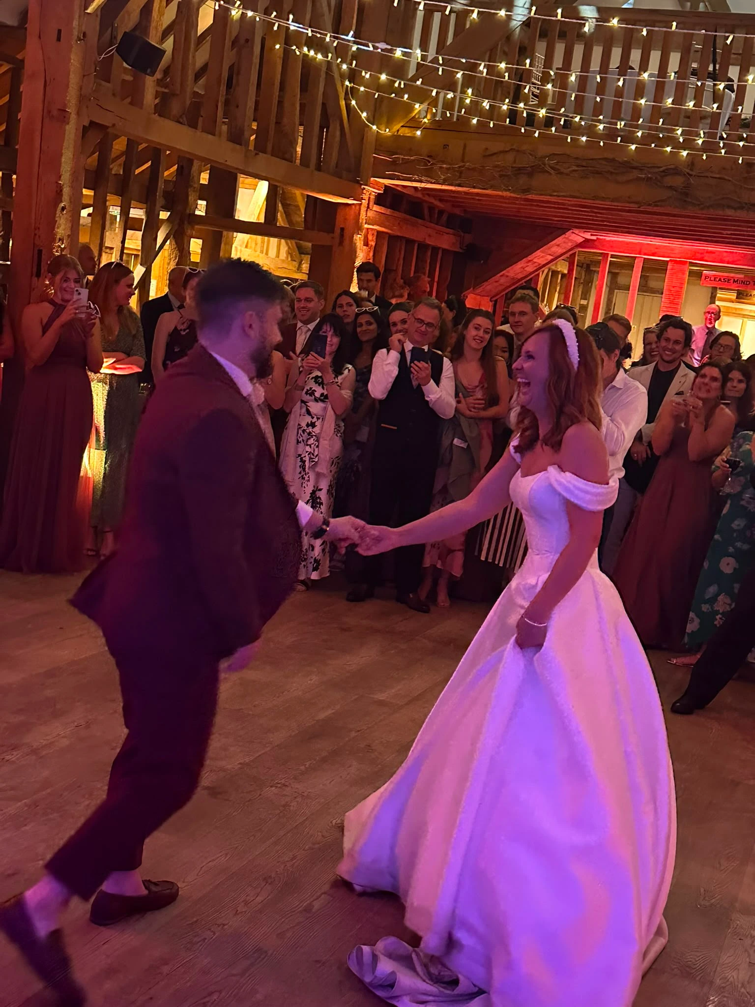 First dance in a beamed barn, guests circled round