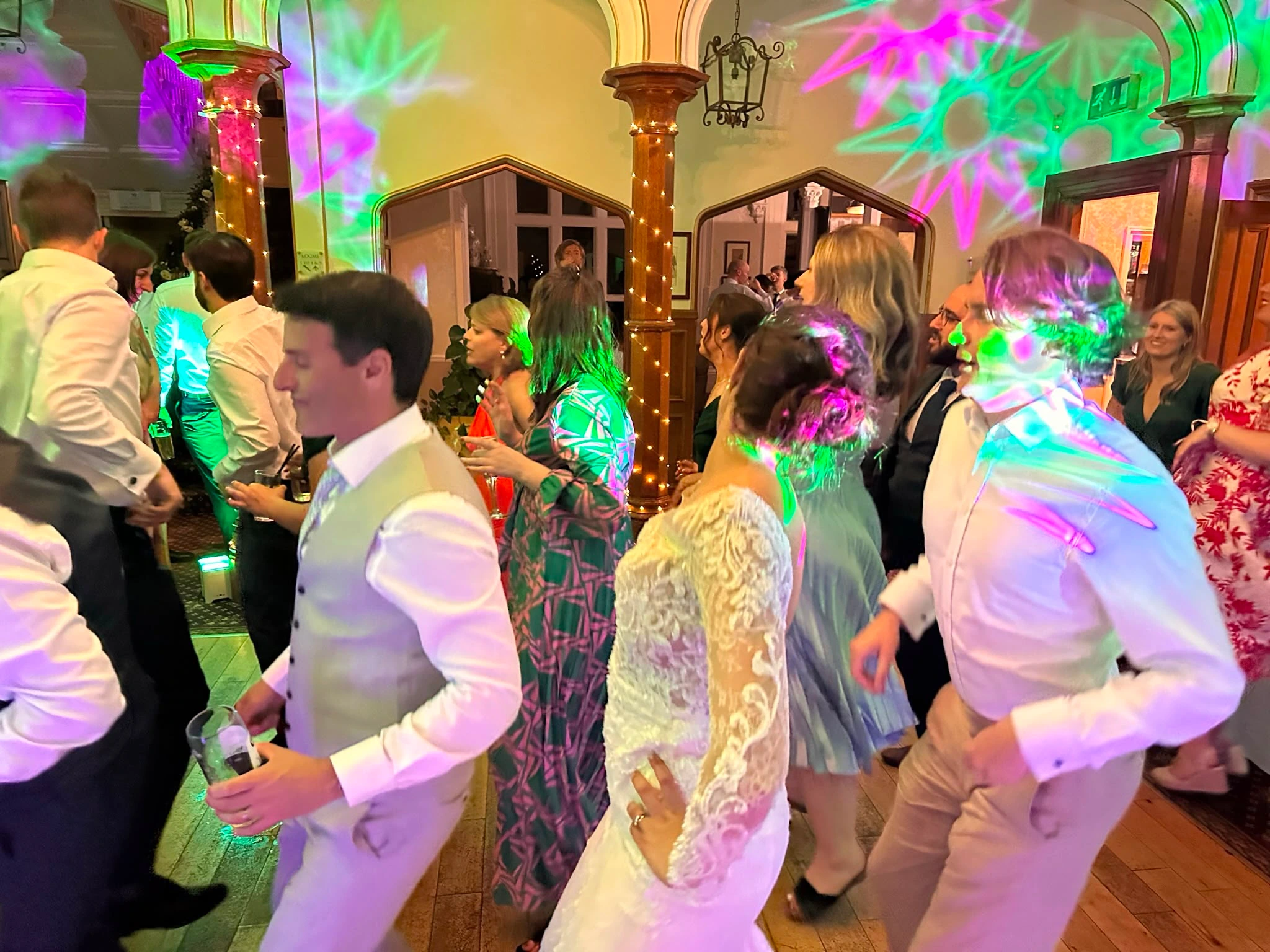 Green and pink gobo patterns washing over a busy floor