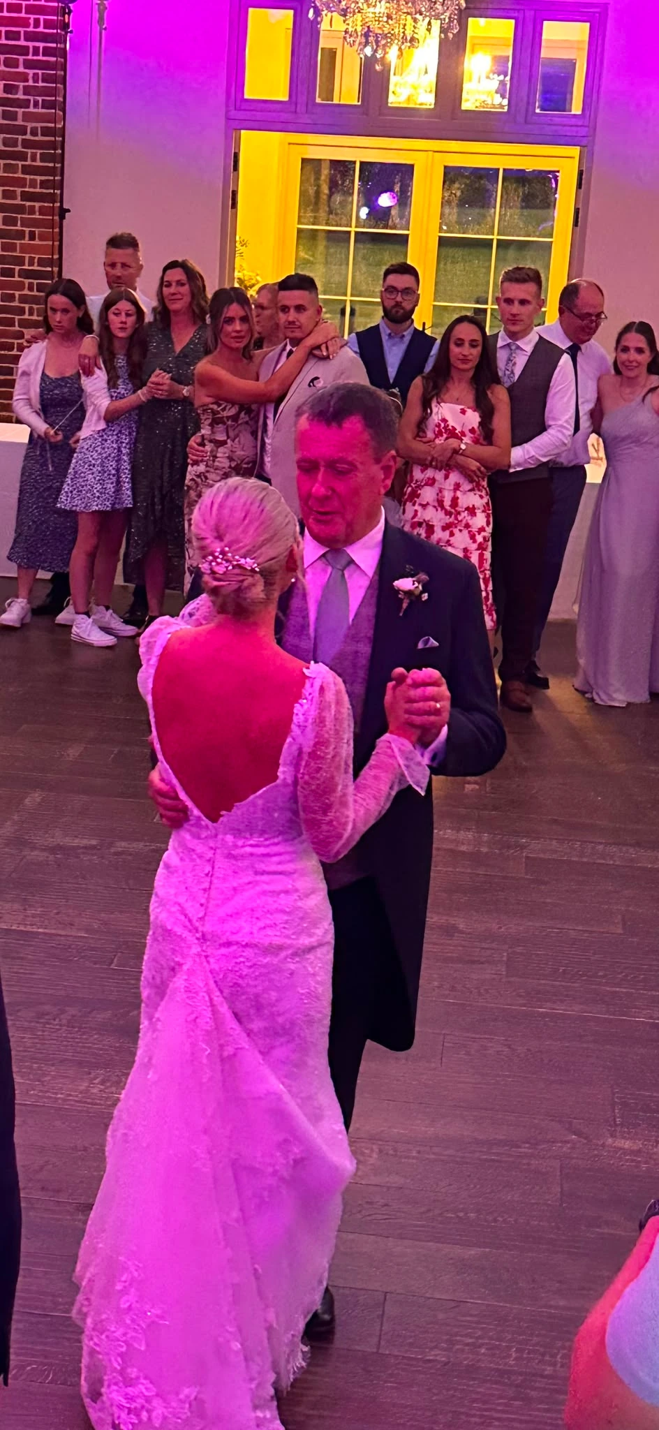 First dance in a courtyard venue, warm light through the windows