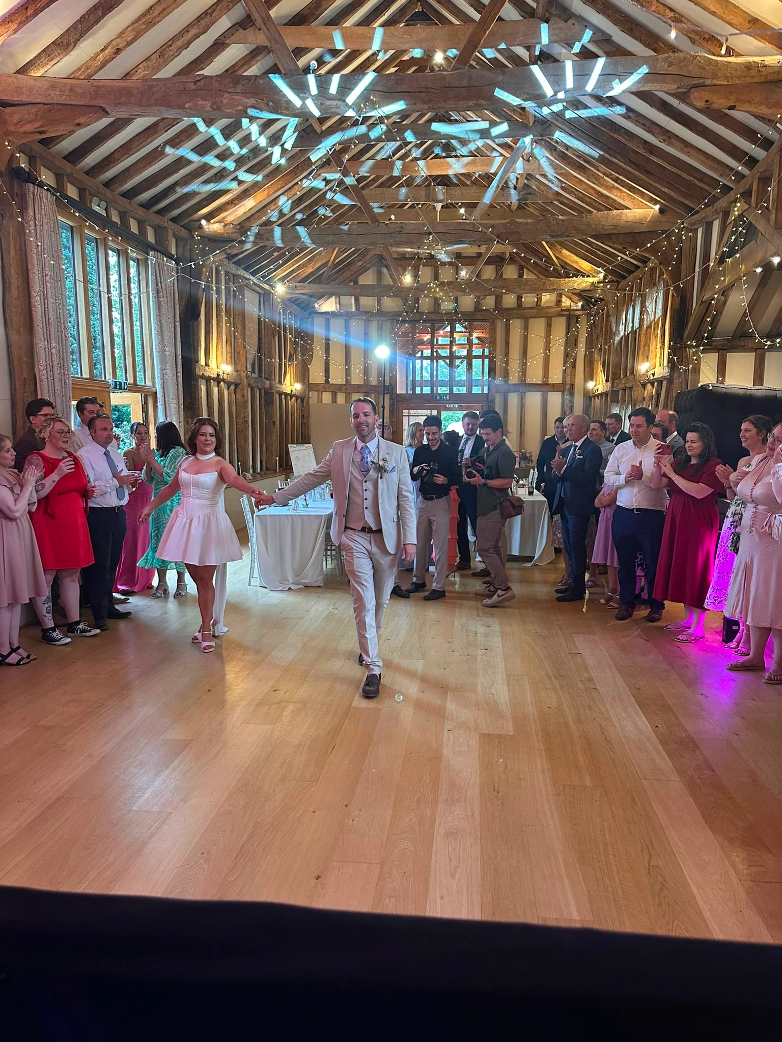 The groom walking into a barn to a room full of guests