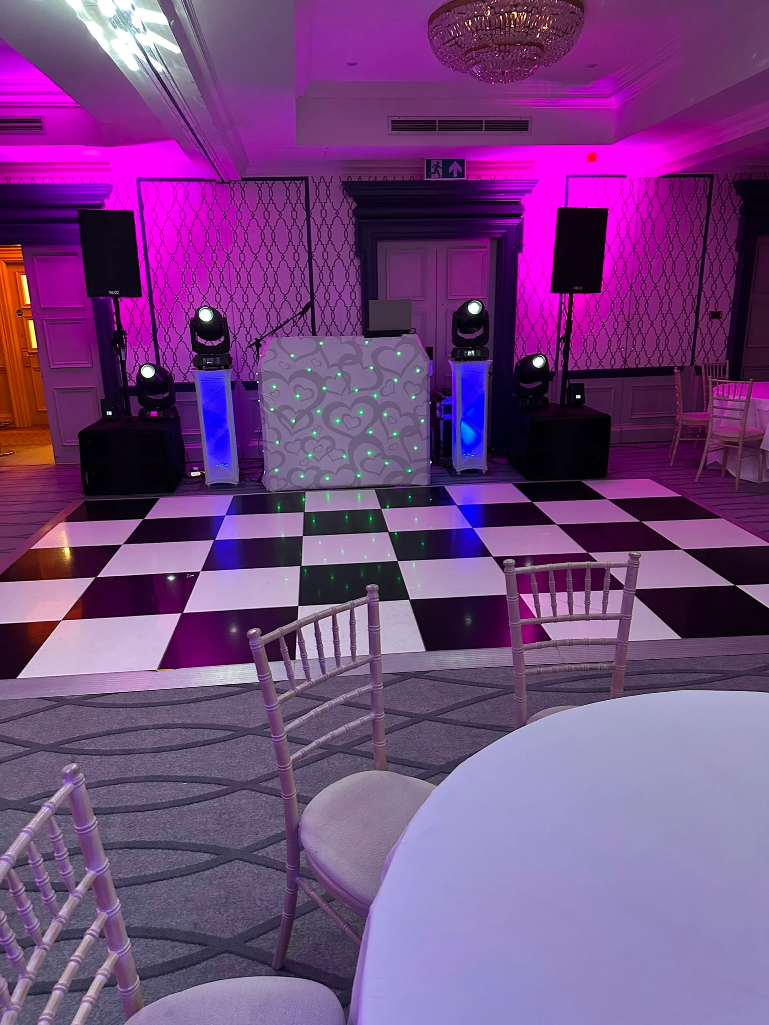 Up-lit ballroom with checkerboard floor and heart booth