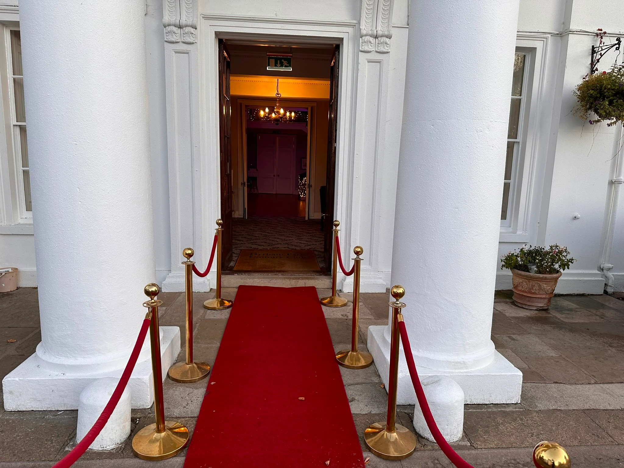 Red carpet and rope barriers at the entrance to a country house venue