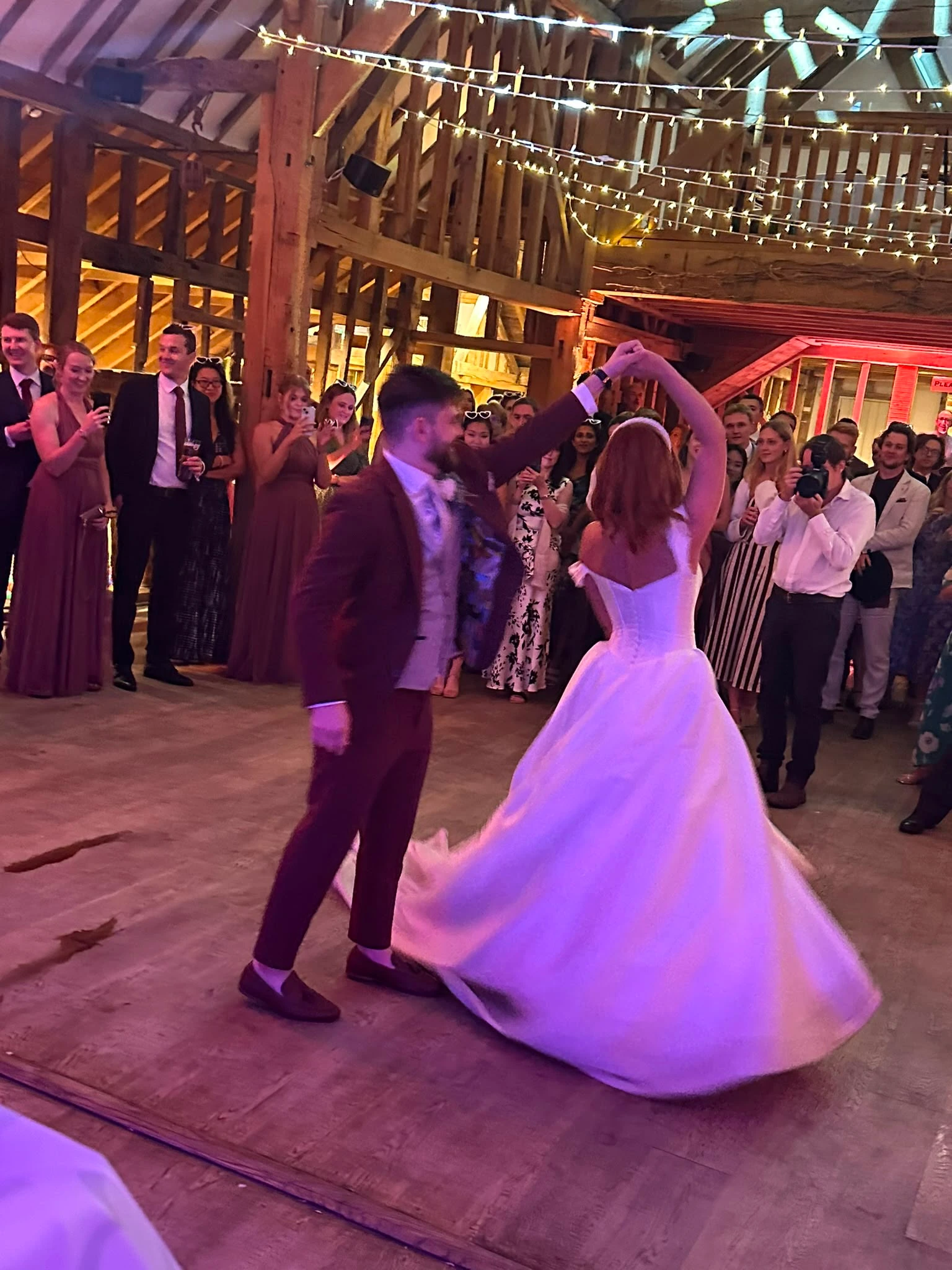The bride spun under her groom's arm in a beamed barn