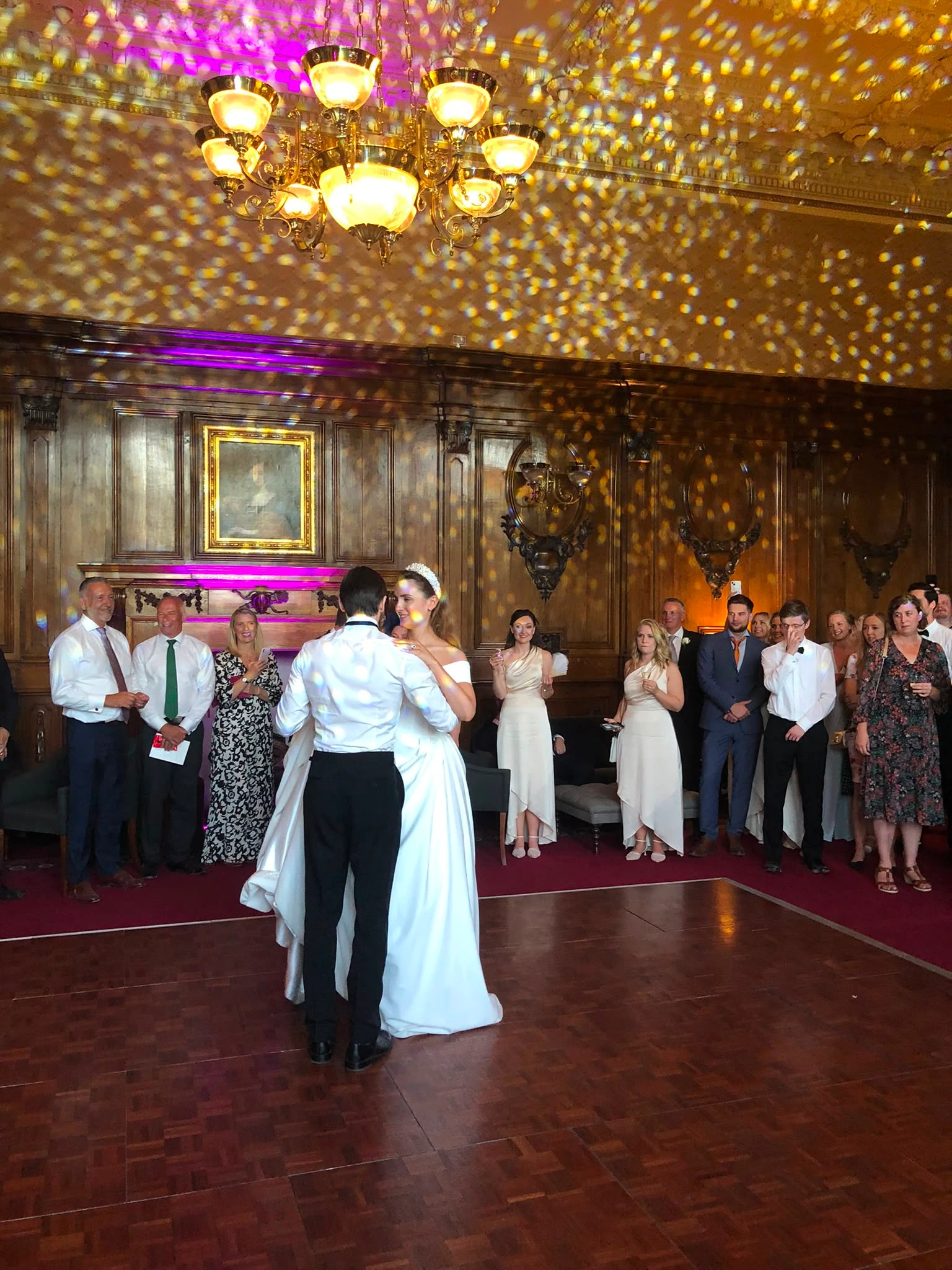 First dance in an oak-panelled hall under gold speckled lighting