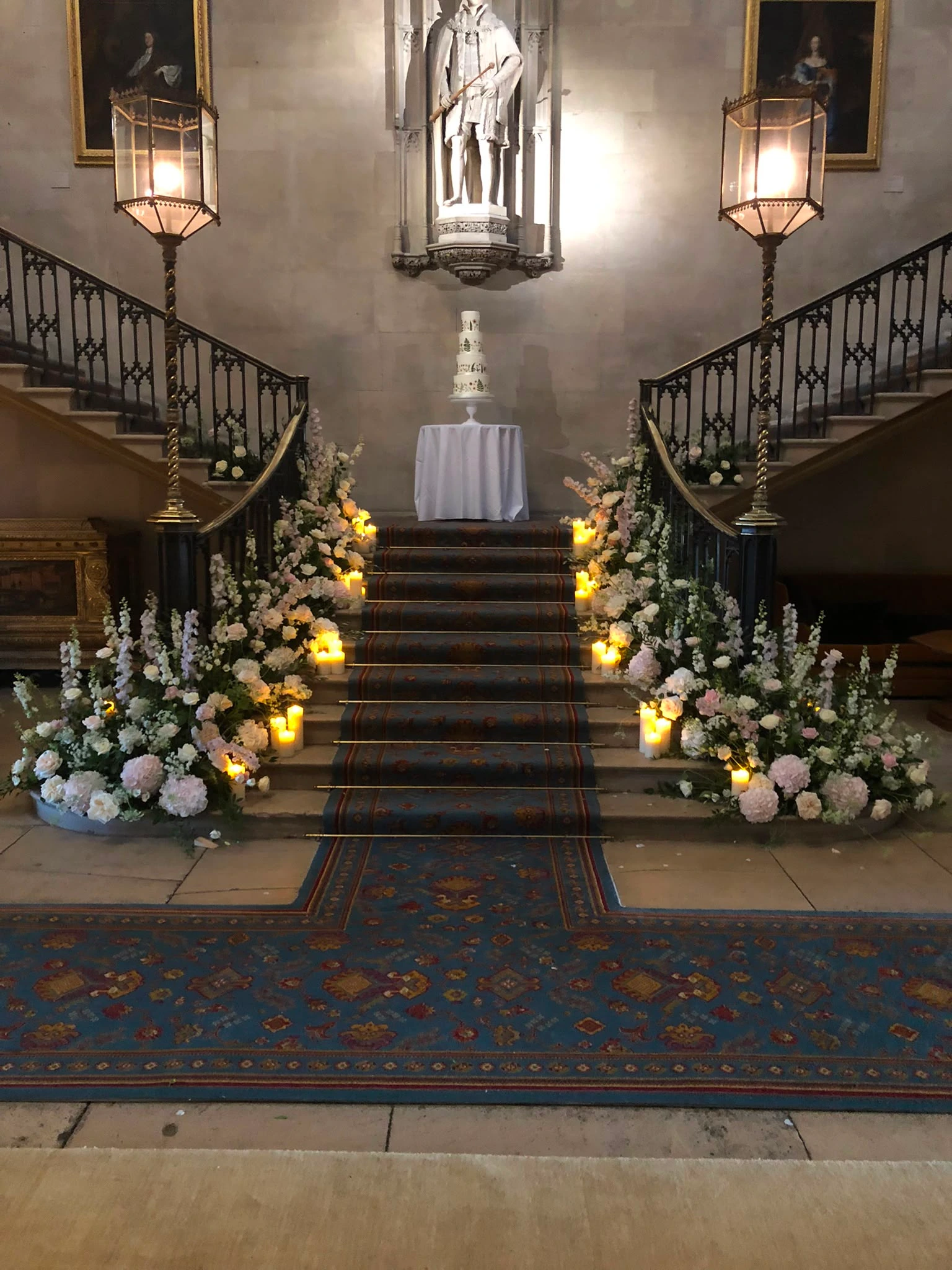 Wedding cake on a grand staircase framed by flowers and candles
