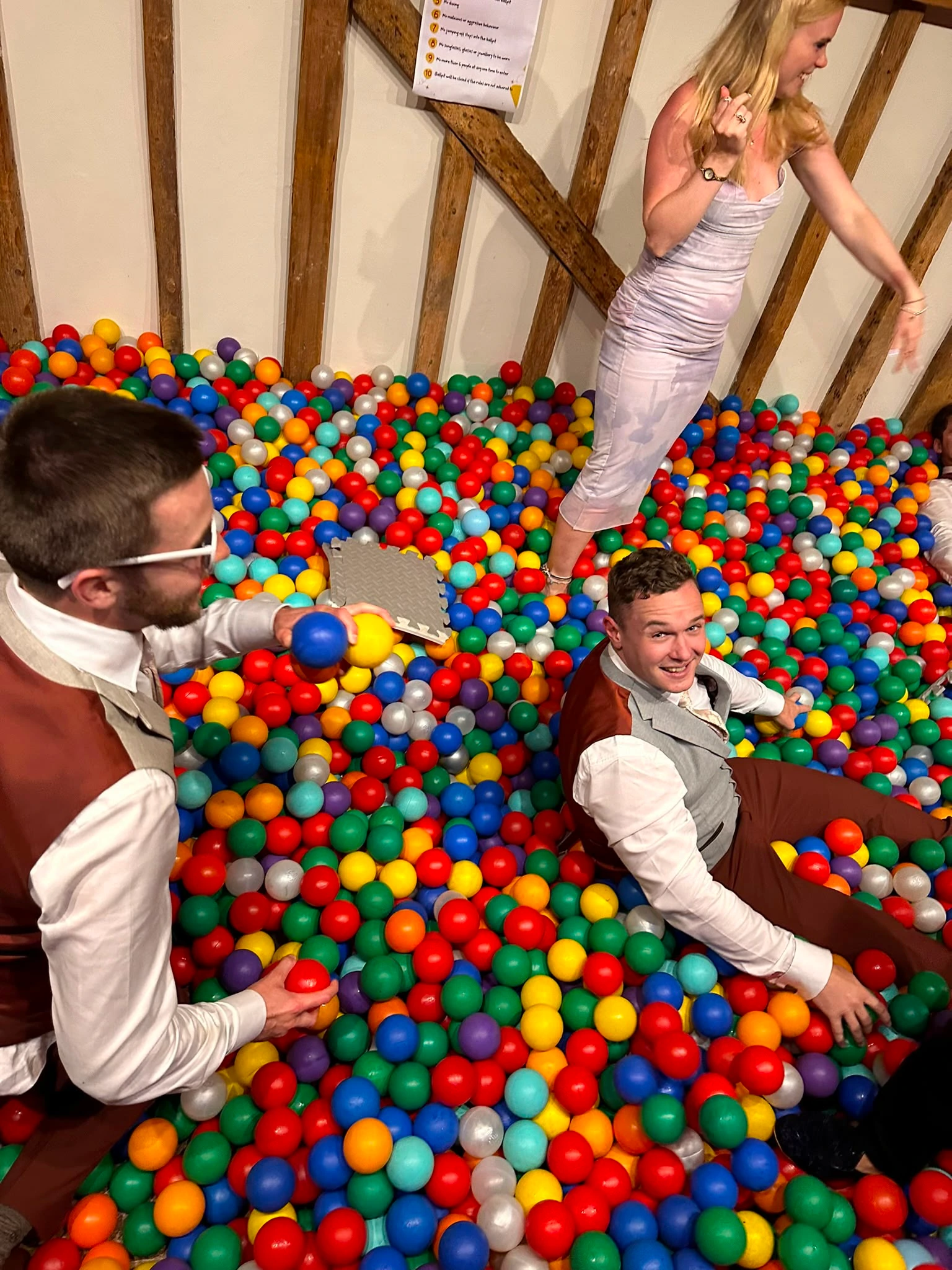 The wedding party larking about in a ball pit