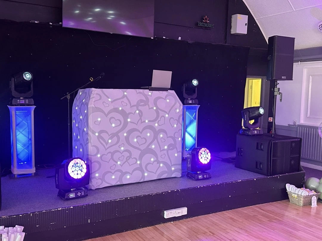 White heart booth raised on a stage with moving heads