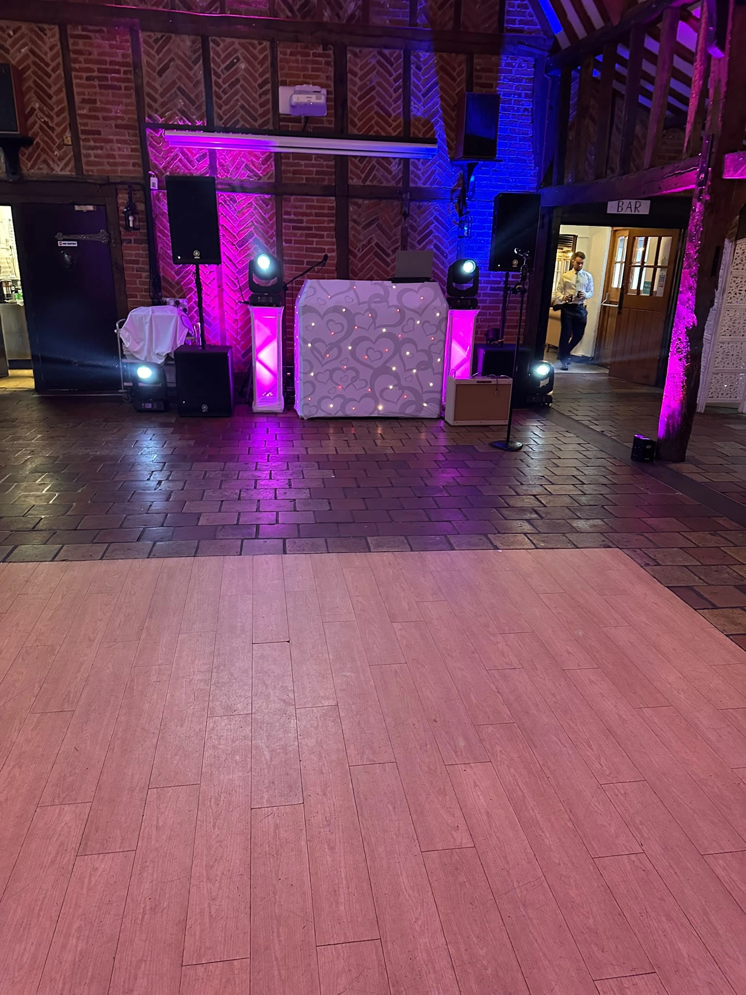 The booth and pink uplighting set up in a beamed barn before the guests came through