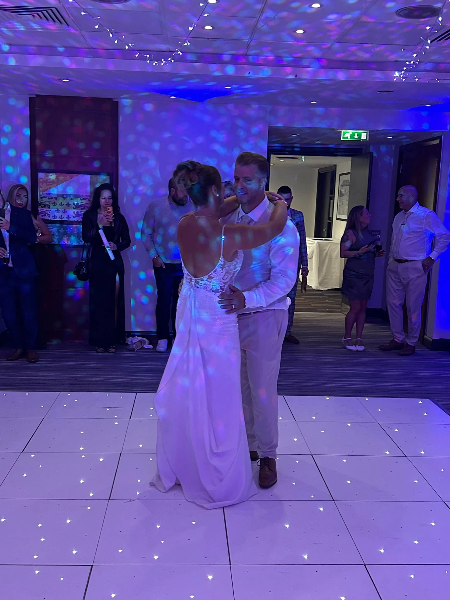 A first dance on the white starlit floor under blue light