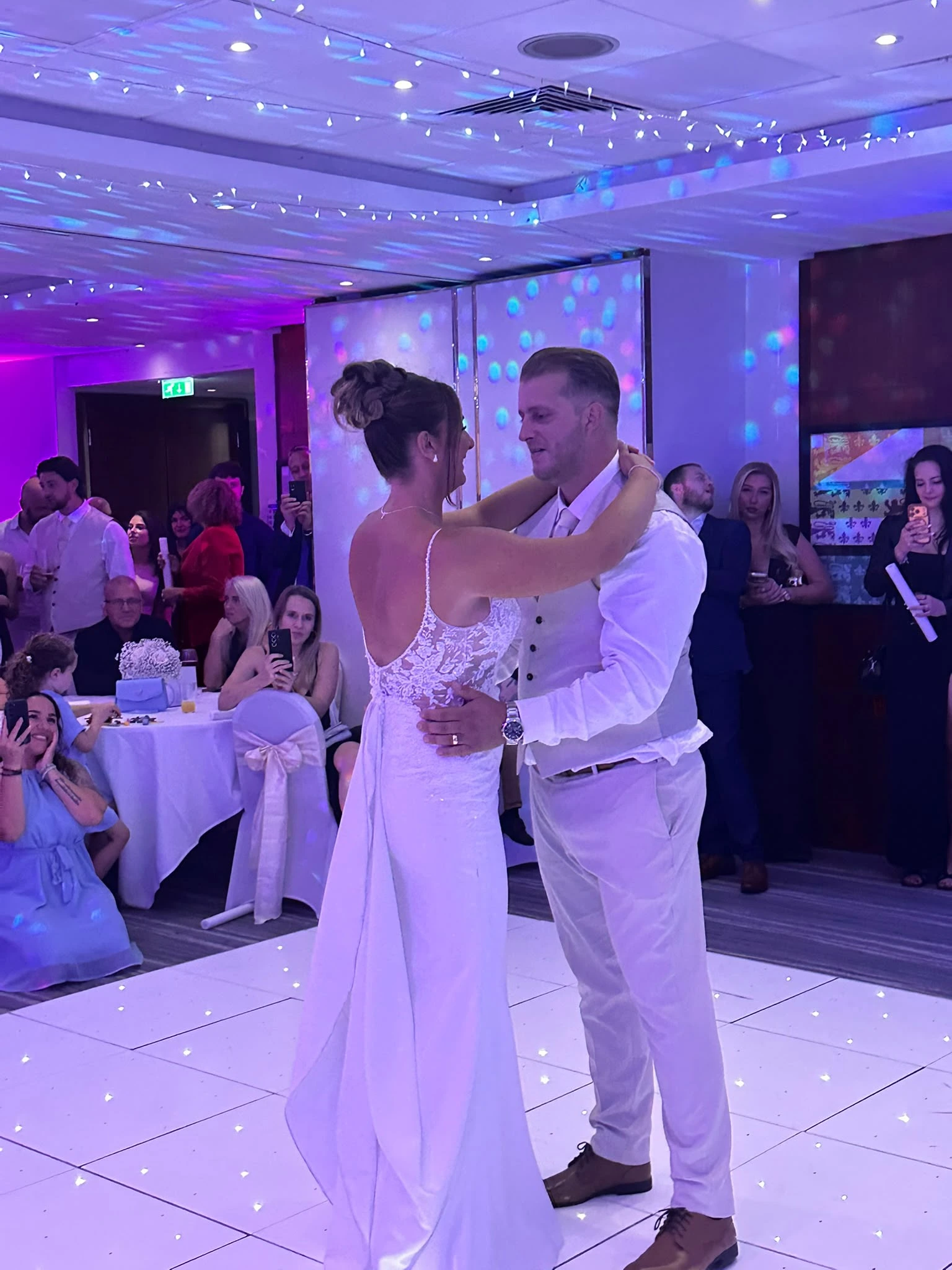 The same first dance, close in, with the room watching from the tables