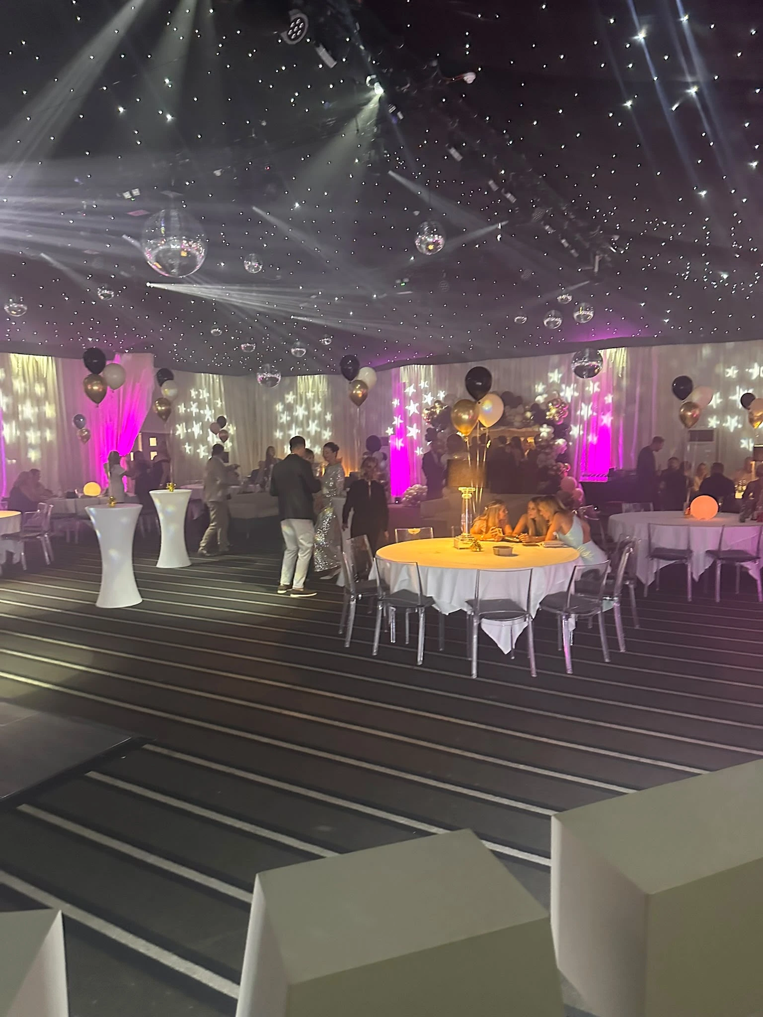 A marquee under star cloth and mirror balls, dressed for a milestone birthday