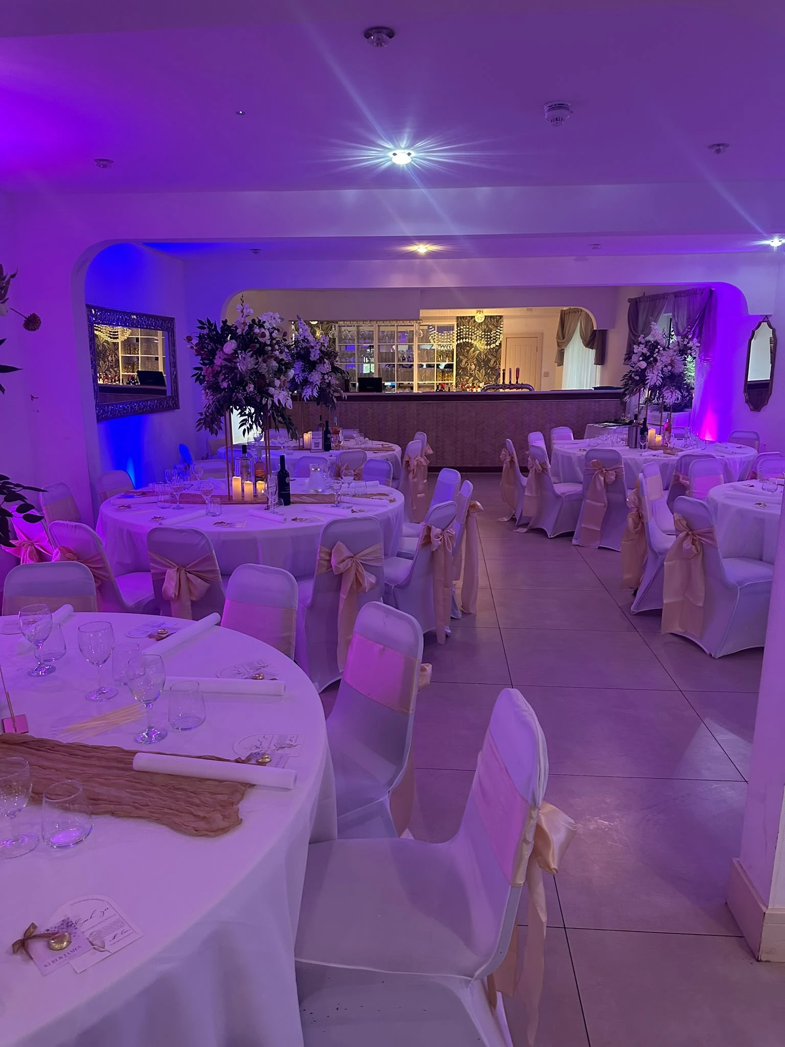 A function room dressed for the wedding breakfast and uplit in purple