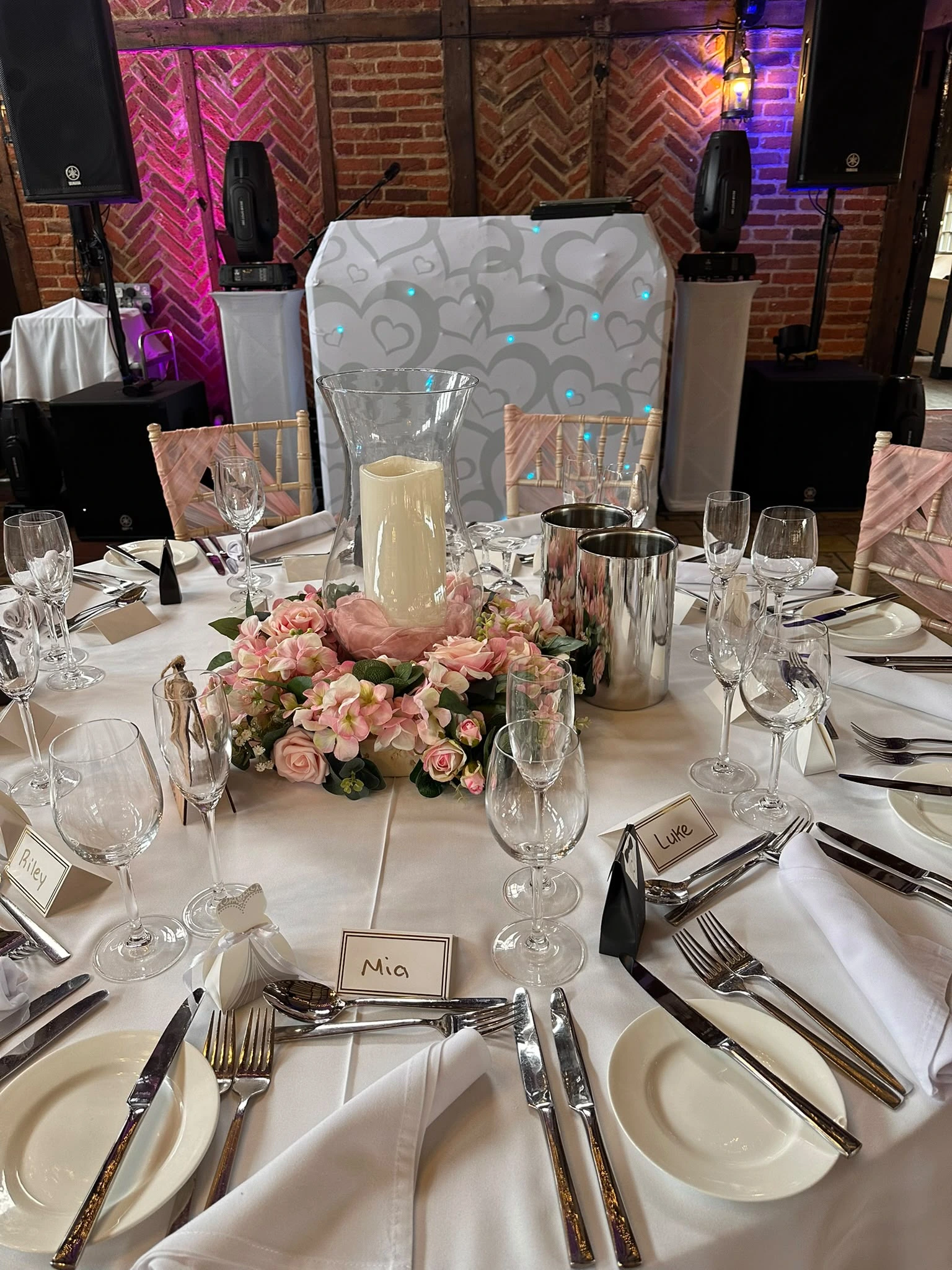 A table laid with a rose and candle centrepiece, the lit booth behind it